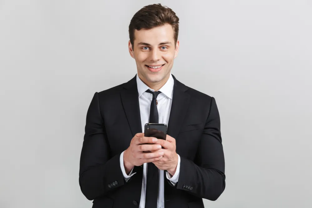 Boldog férfi öltönyben és okostelefonnal